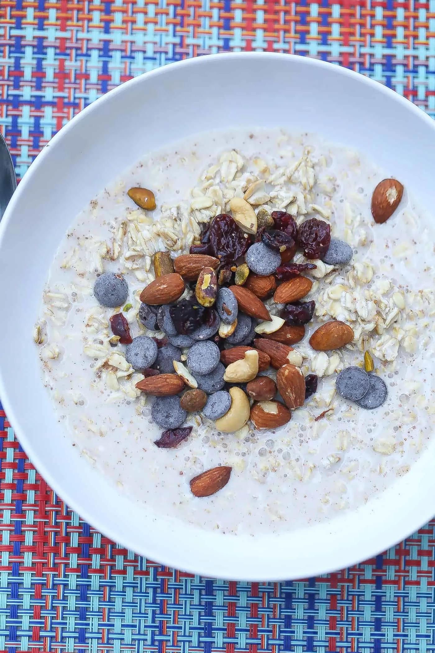 overnight oatmeal with fonio topped with trail mix in a white bowl