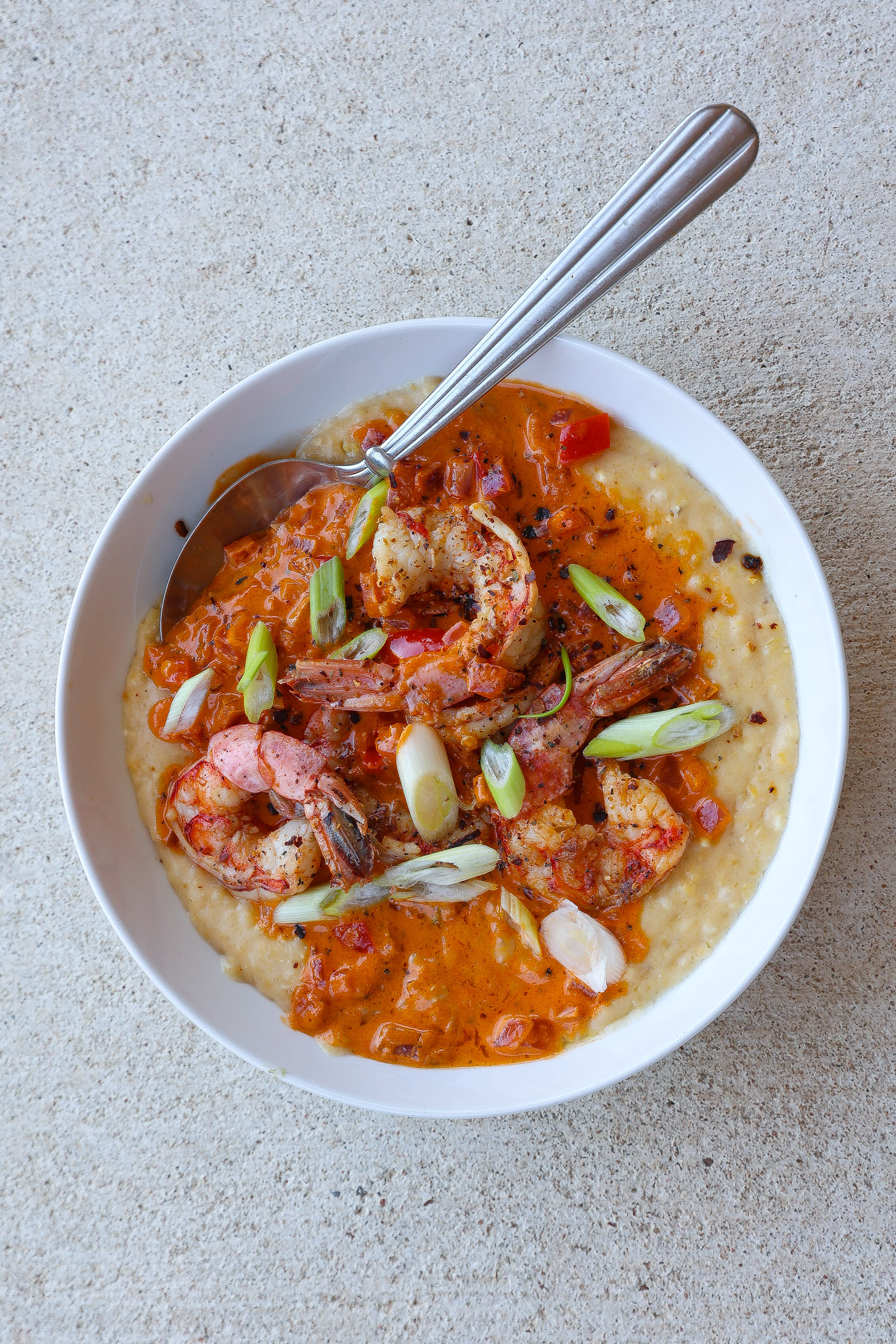 shrimp and grits in a bowl topped with red pepper sauce