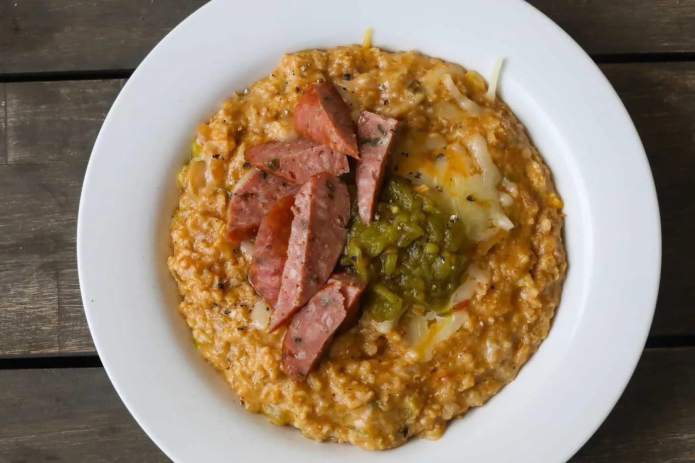 oatmeal with sausage, cheese, and peppers in a white bowl