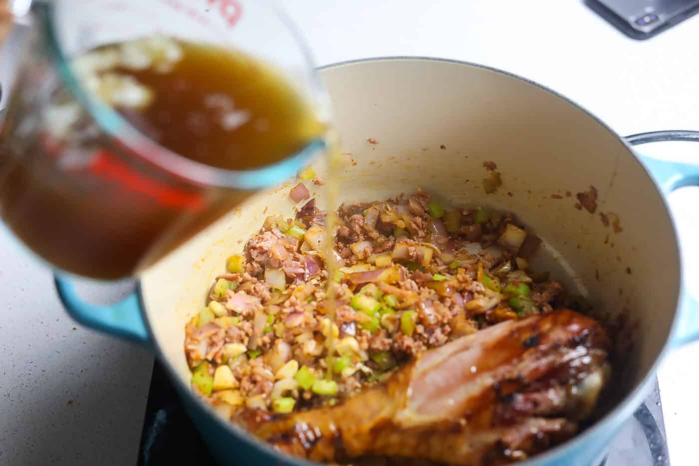 pouring stock into blackeyed peas pot