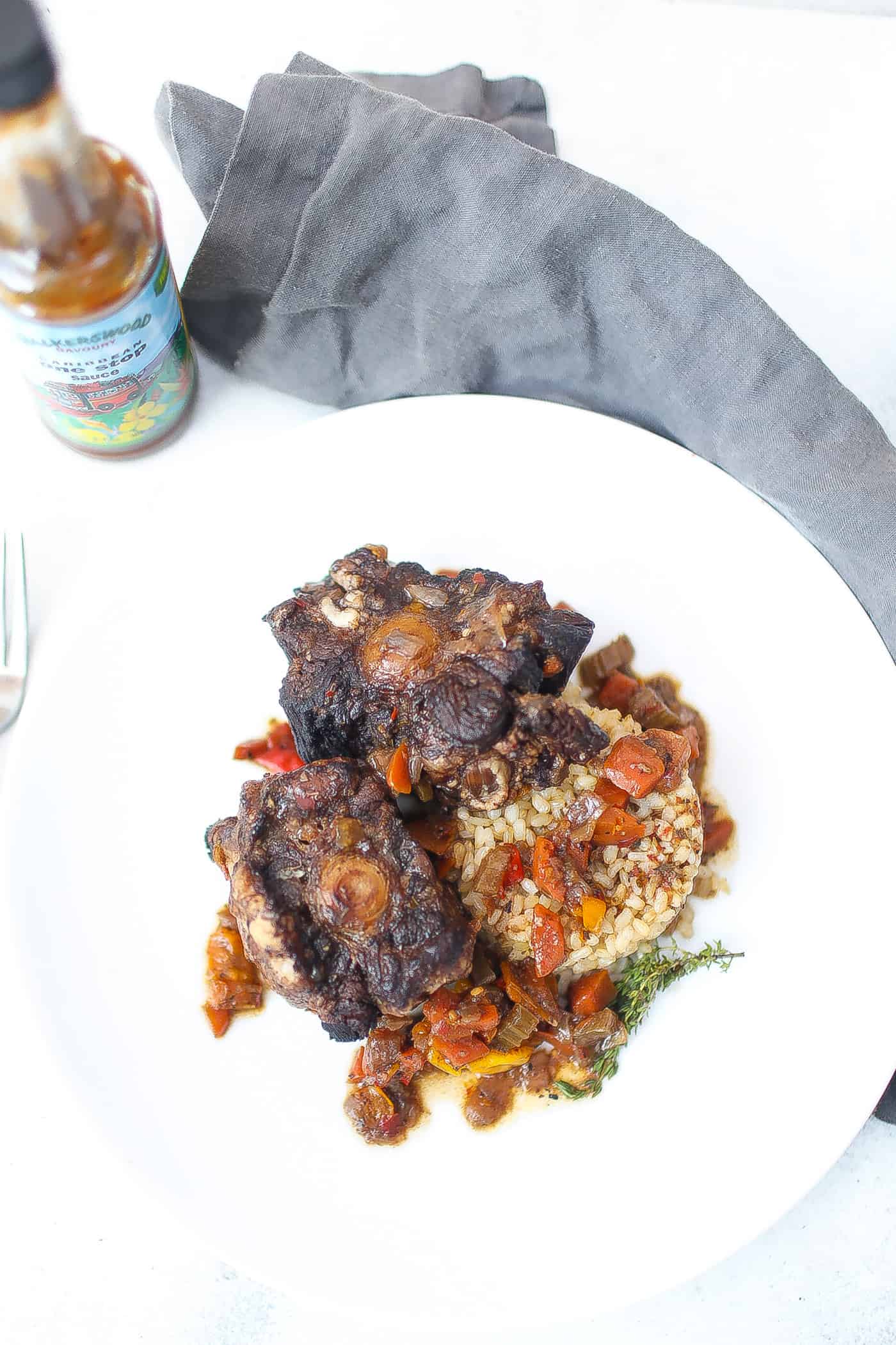 jamaica oxtail on white plate with brown rice