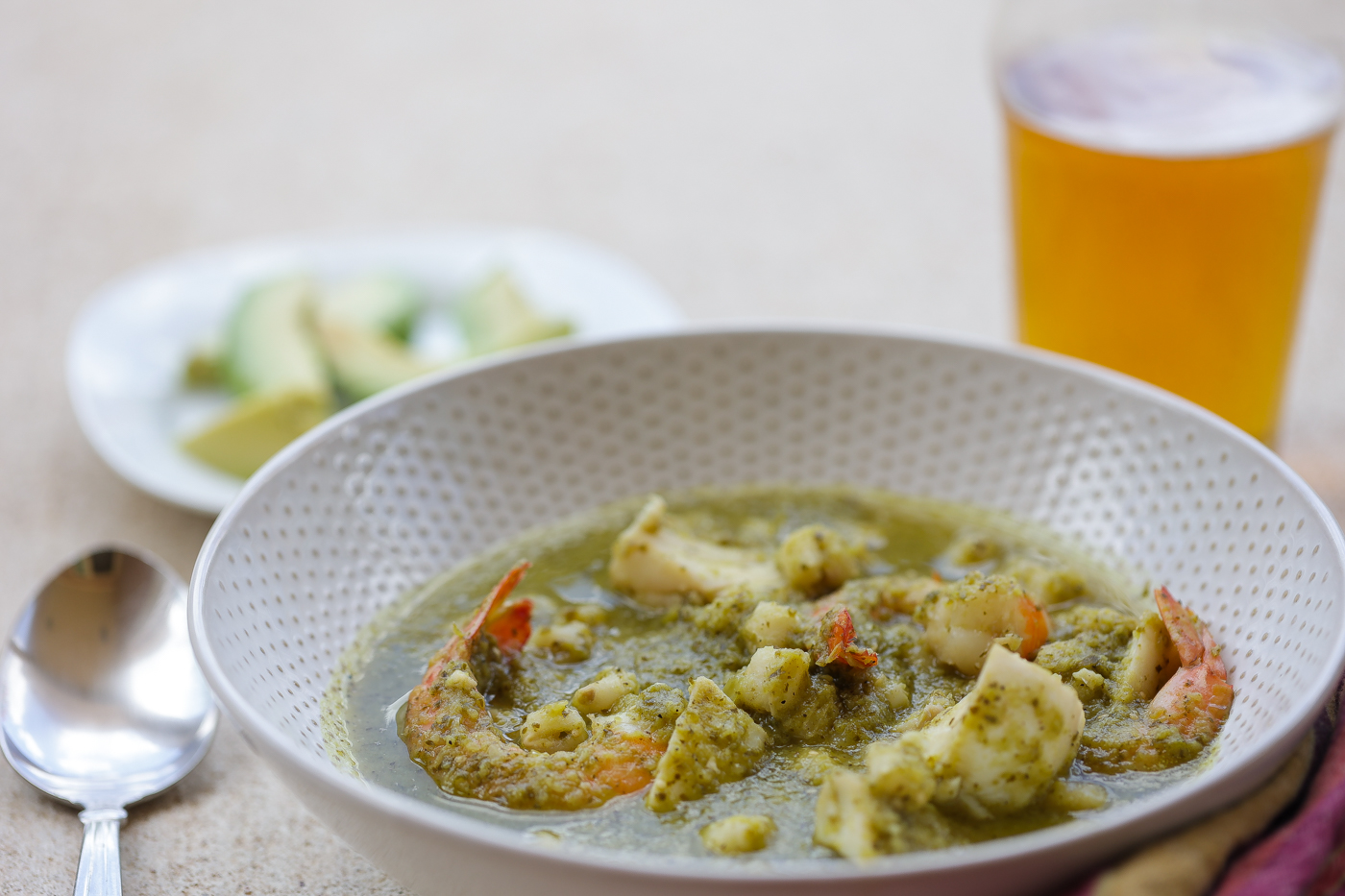 posole verde in a white bowl with avocado