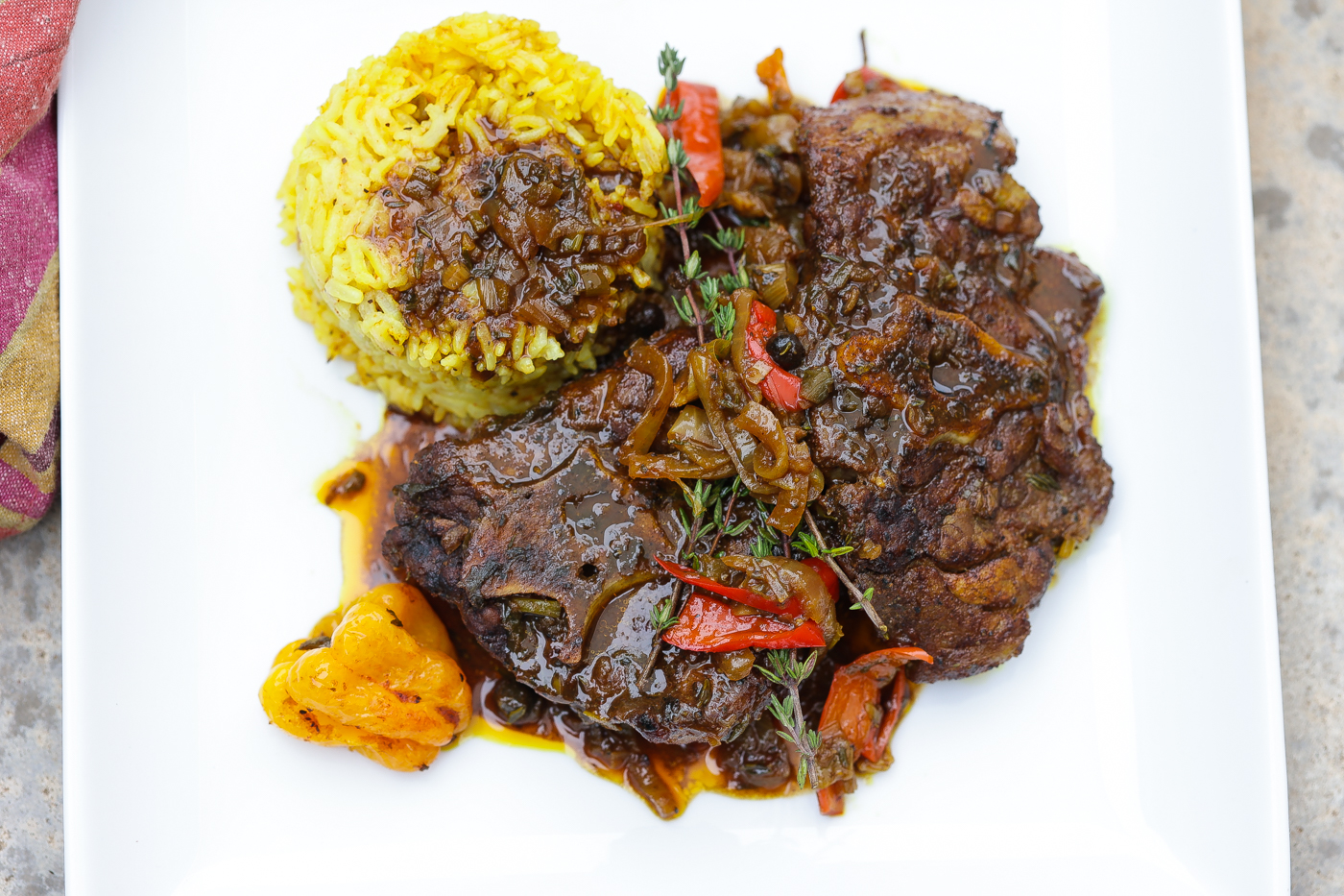 brown stew lamb necks with rice on white plate