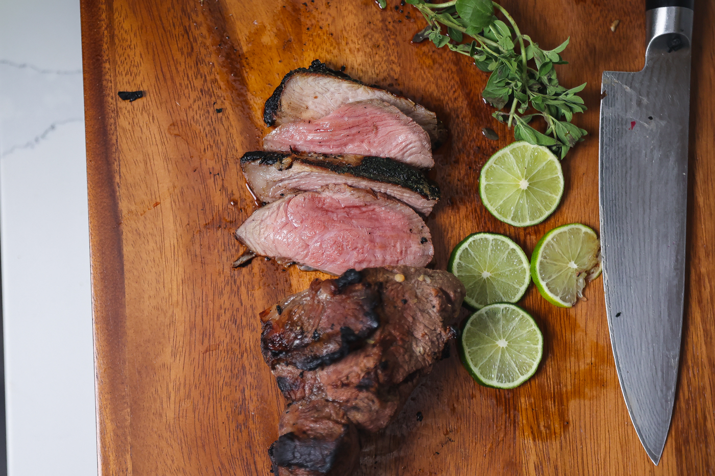 grilled butterflied leg of lamb on cutting board