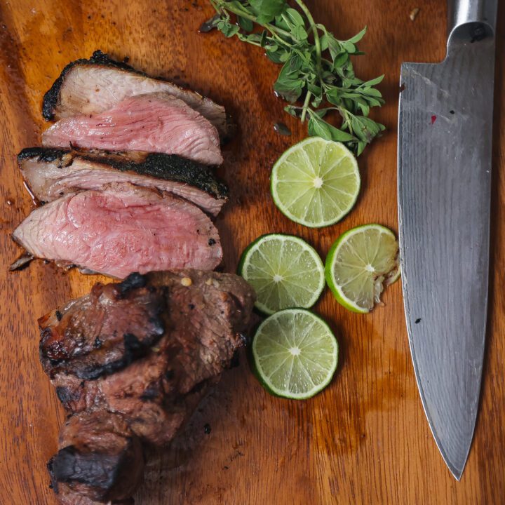 grilled butterflied leg of lamb on cutting board