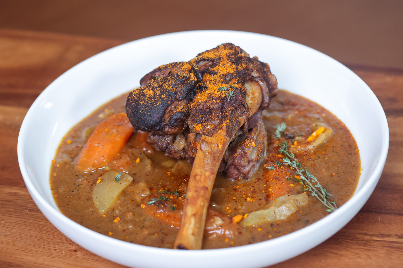 braised lamb shank with sauce on white plate