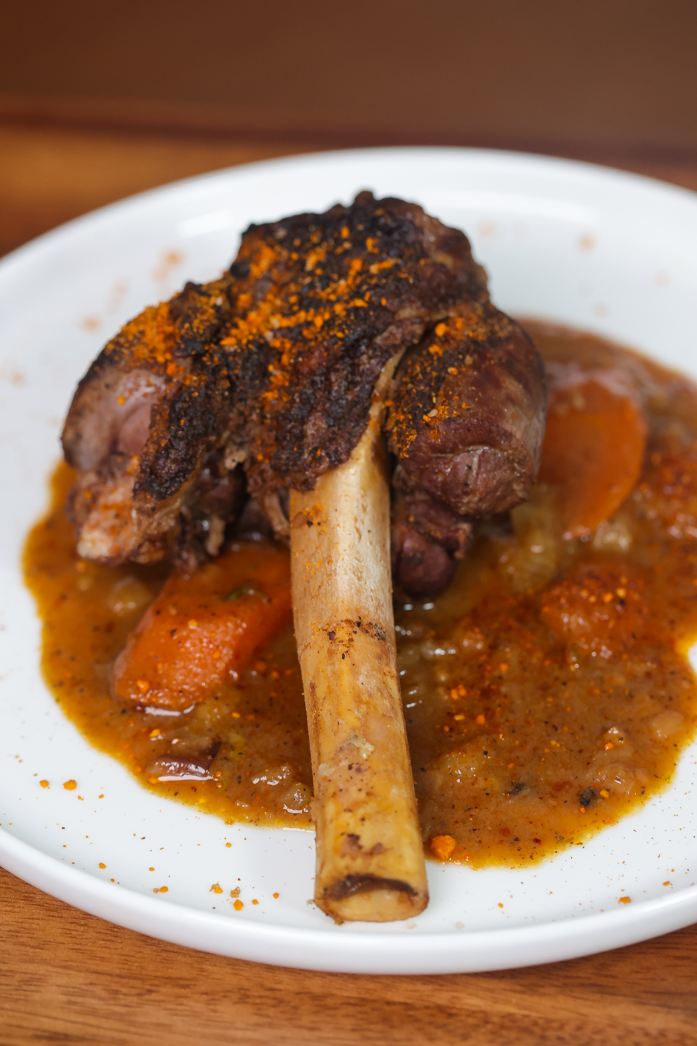 braised lamb shank with sauce on white plate