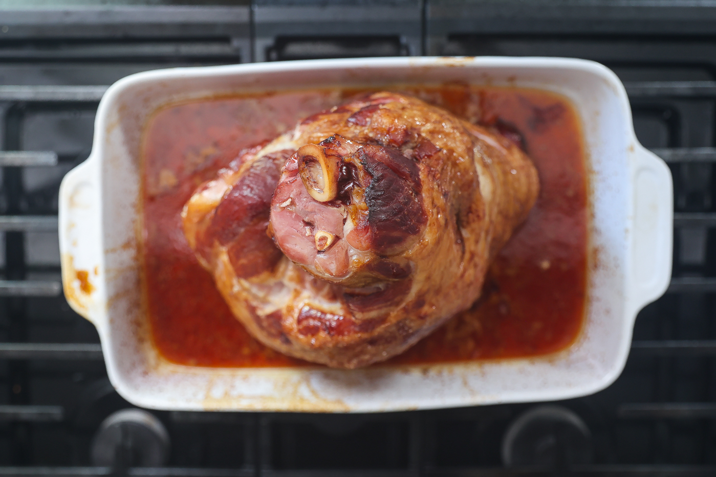 A sliced maple glazed ham placed on a white platter.