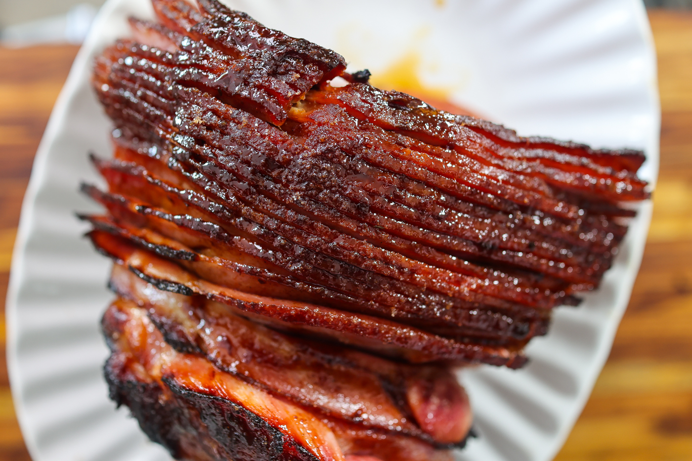 A sliced maple glazed ham placed on a white platter.