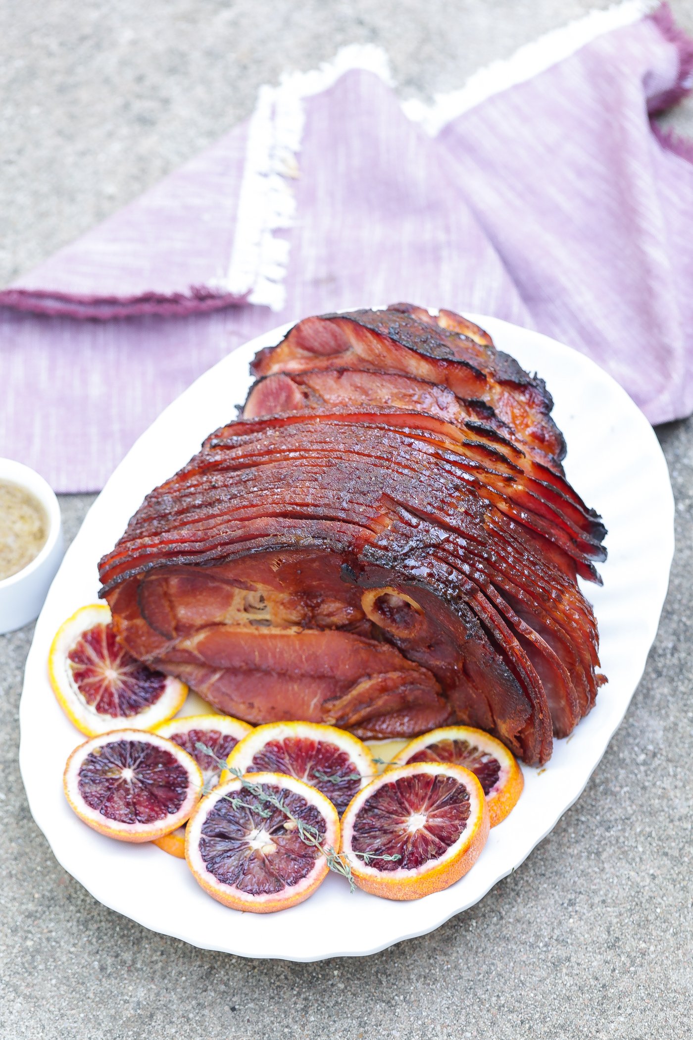 A sliced maple glazed ham placed on a white platter.