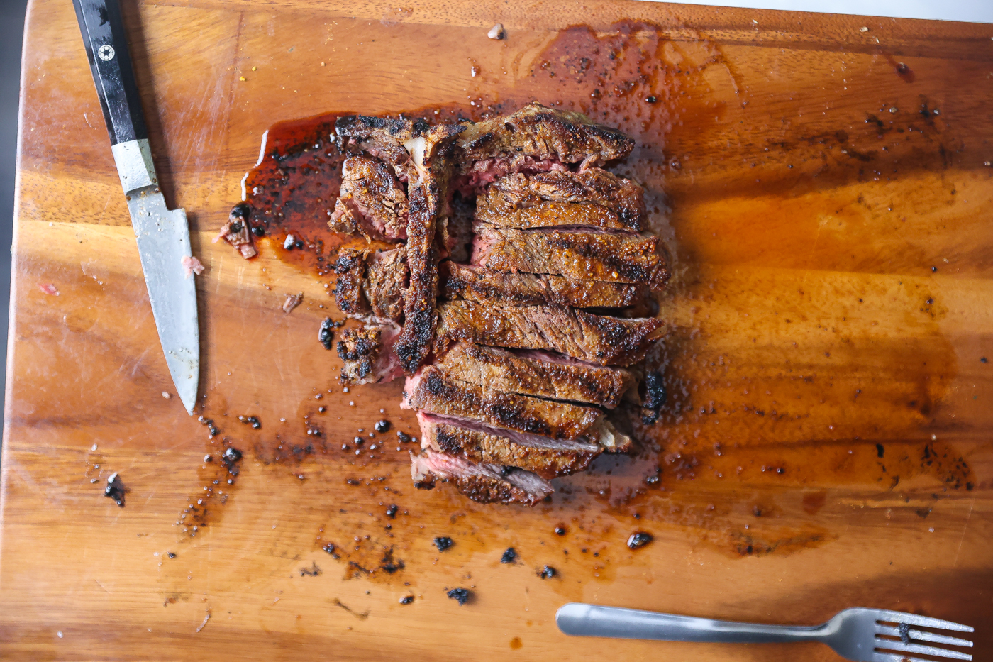 sliced grilled t-bone steak on cutting board