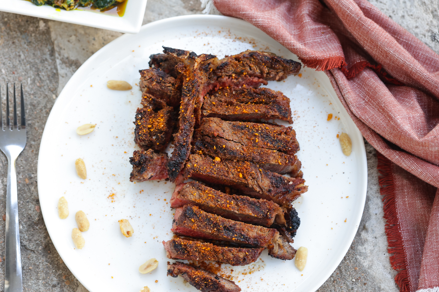 grilled t-bone steak with suya spice on white plate