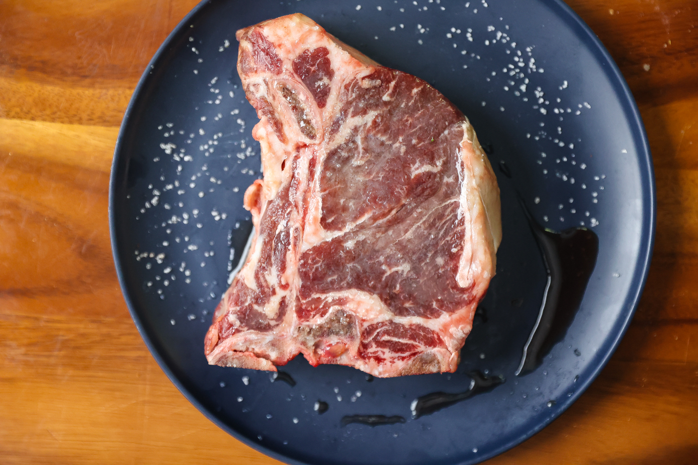 salted raw t-bone steak on plate