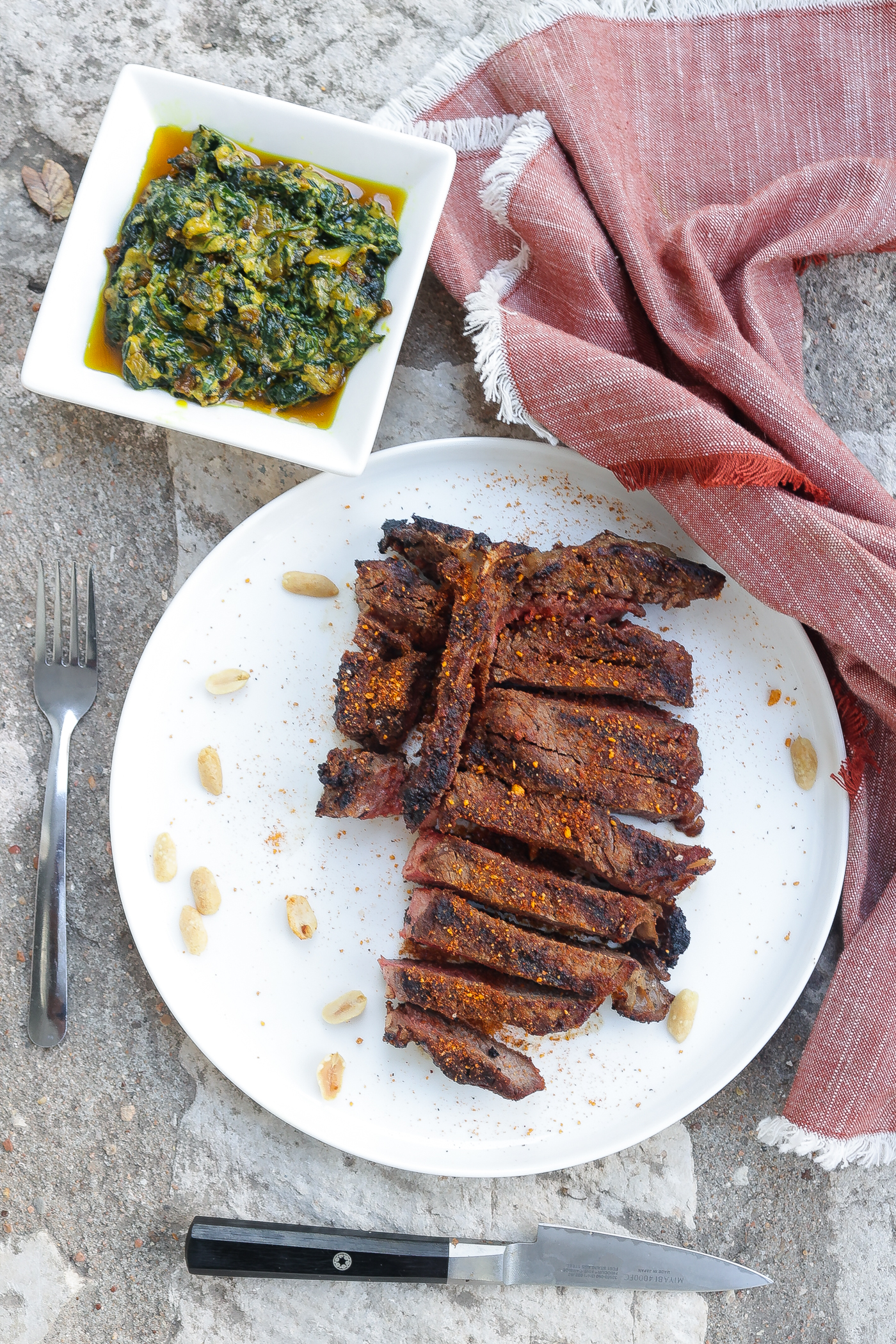 grilled t-bone steak with suya spice on white plate