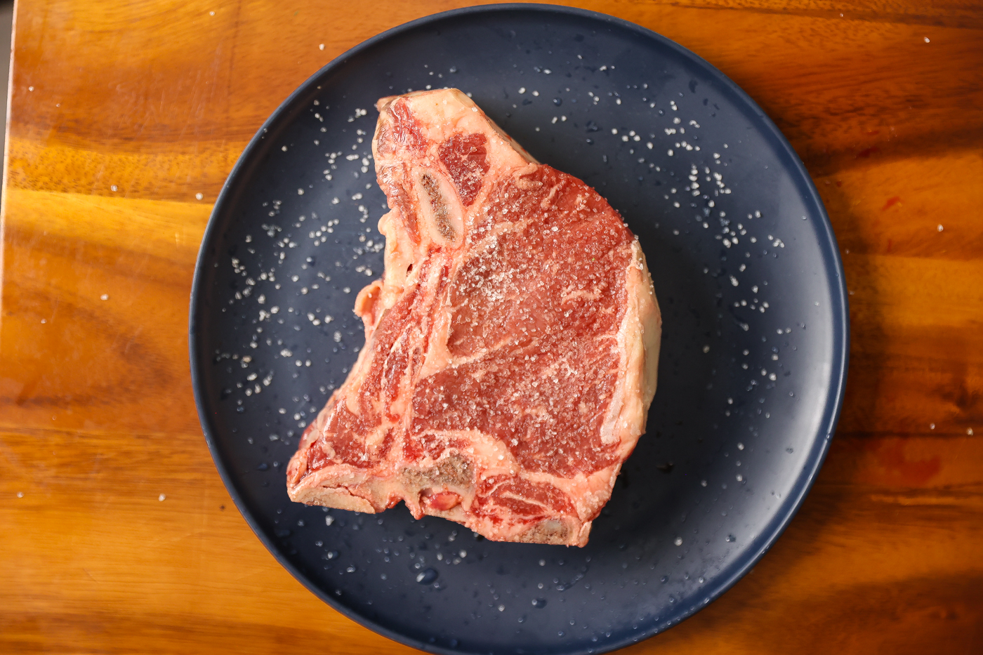 salted raw t-bone steak on plate