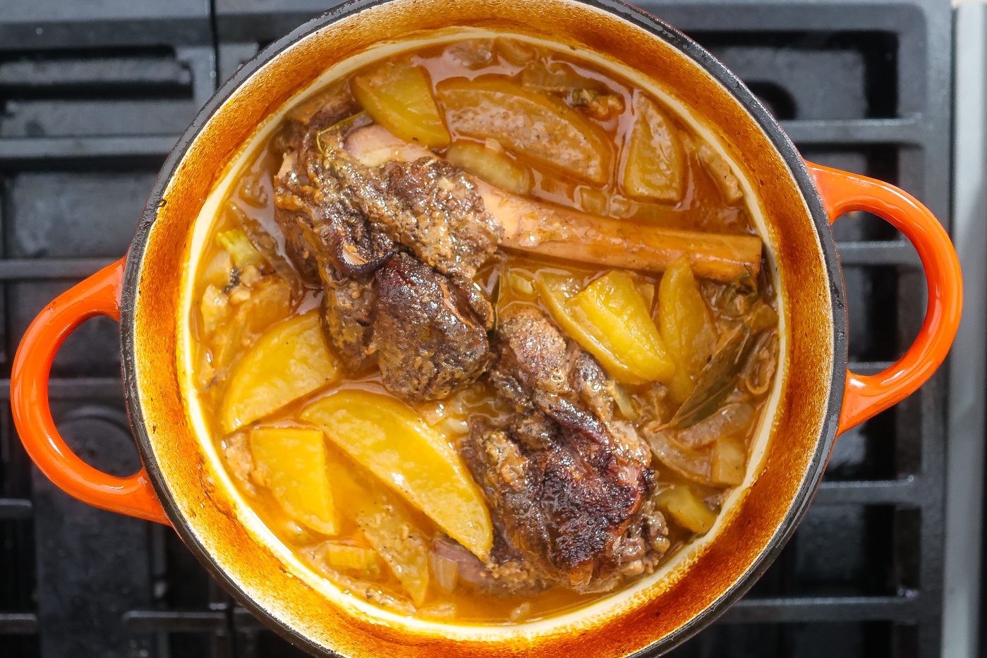 lamb shanks cooking in pot with braising liquid