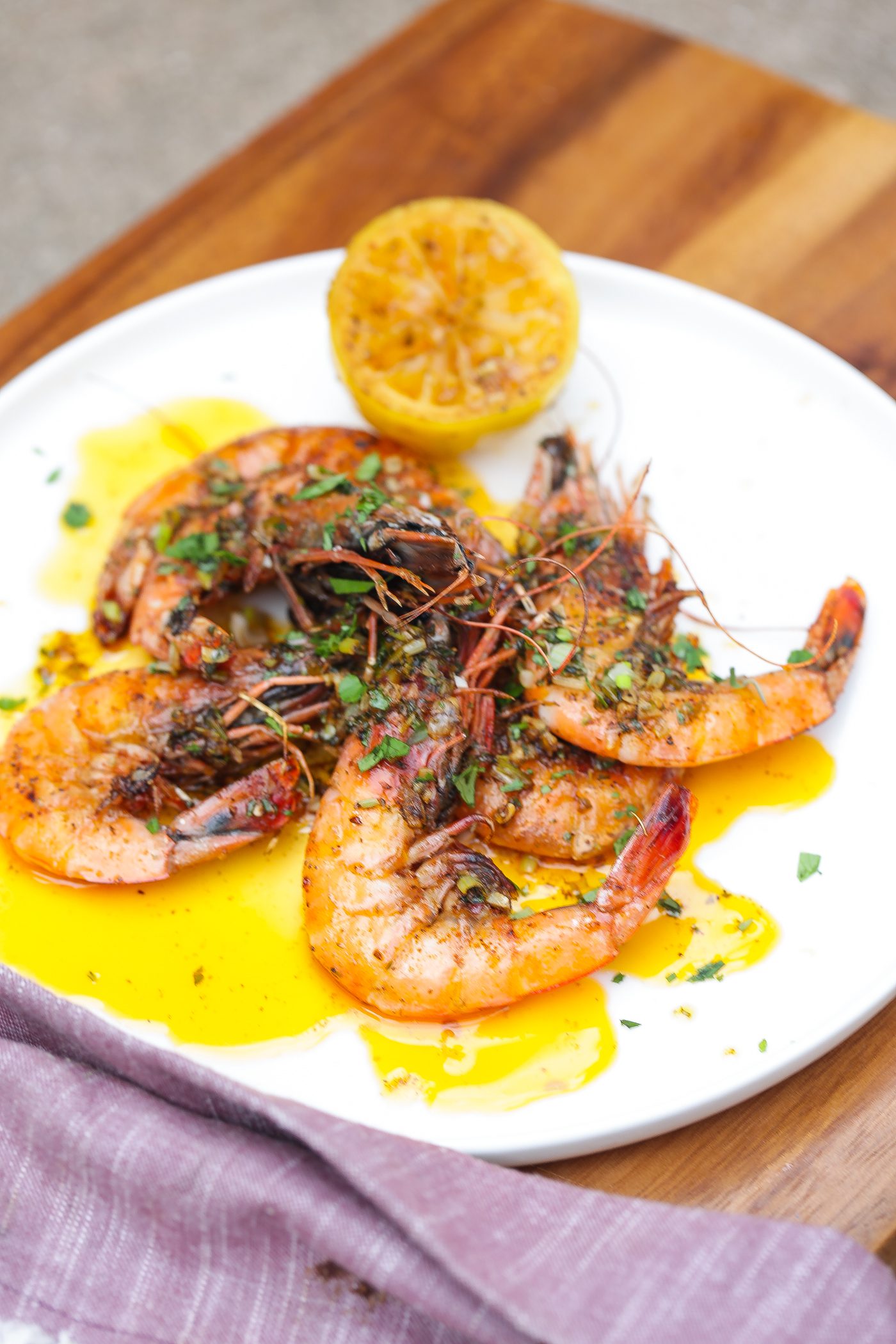 lemon garlic butter shrimp stacked on white plate topped with fresh cilantro